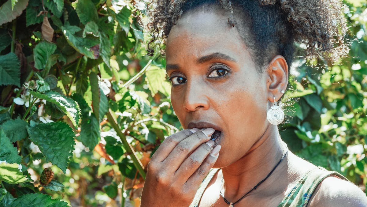 African American woman enjoying fresh berries in a sunlit garden. Vibrant and healthy lifestyle imagery.