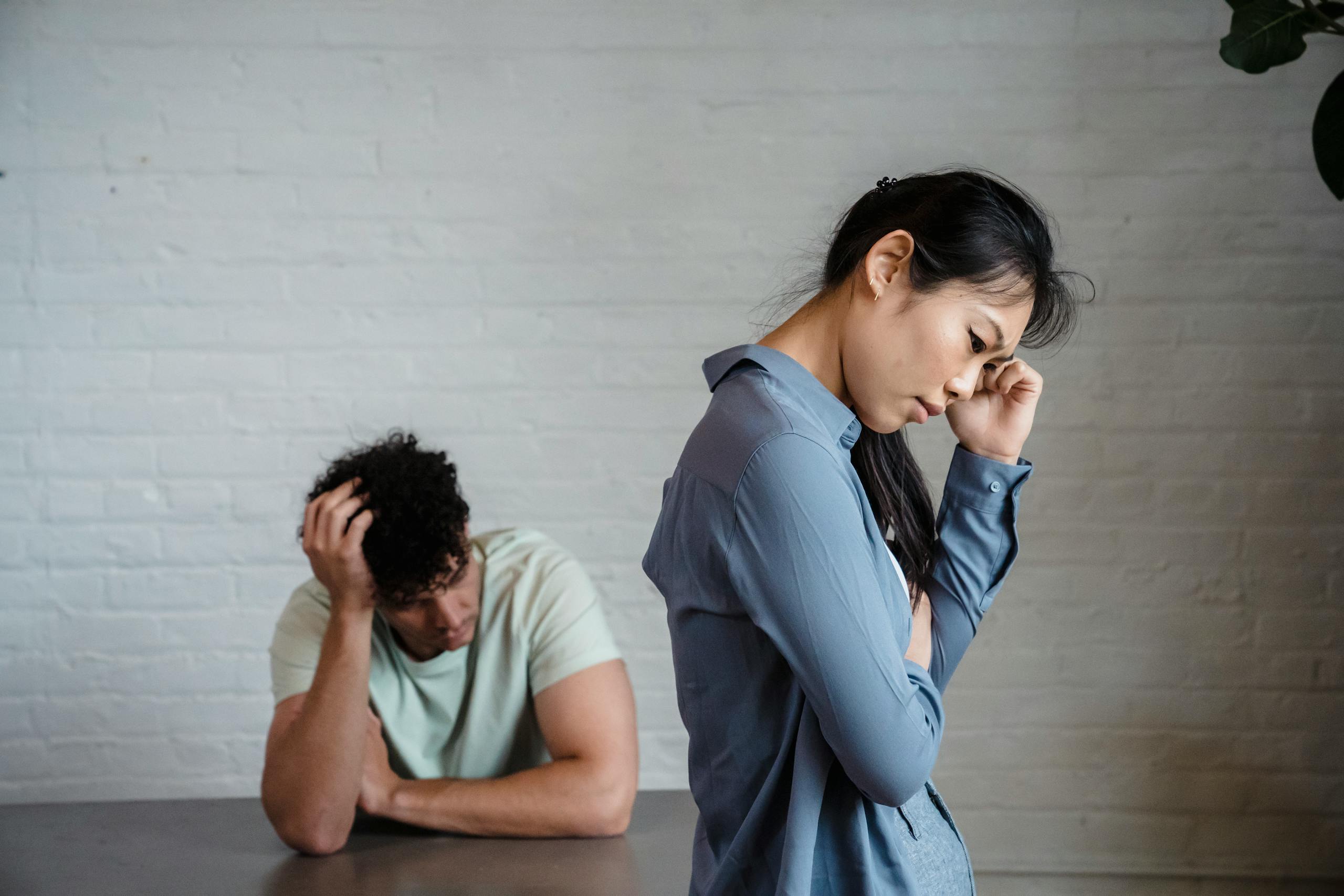 7 Shocking Ways Heartbreak Changes People Permanently 1 An Asian woman and man feeling misunderstood and frustrated in a relationship indoors.