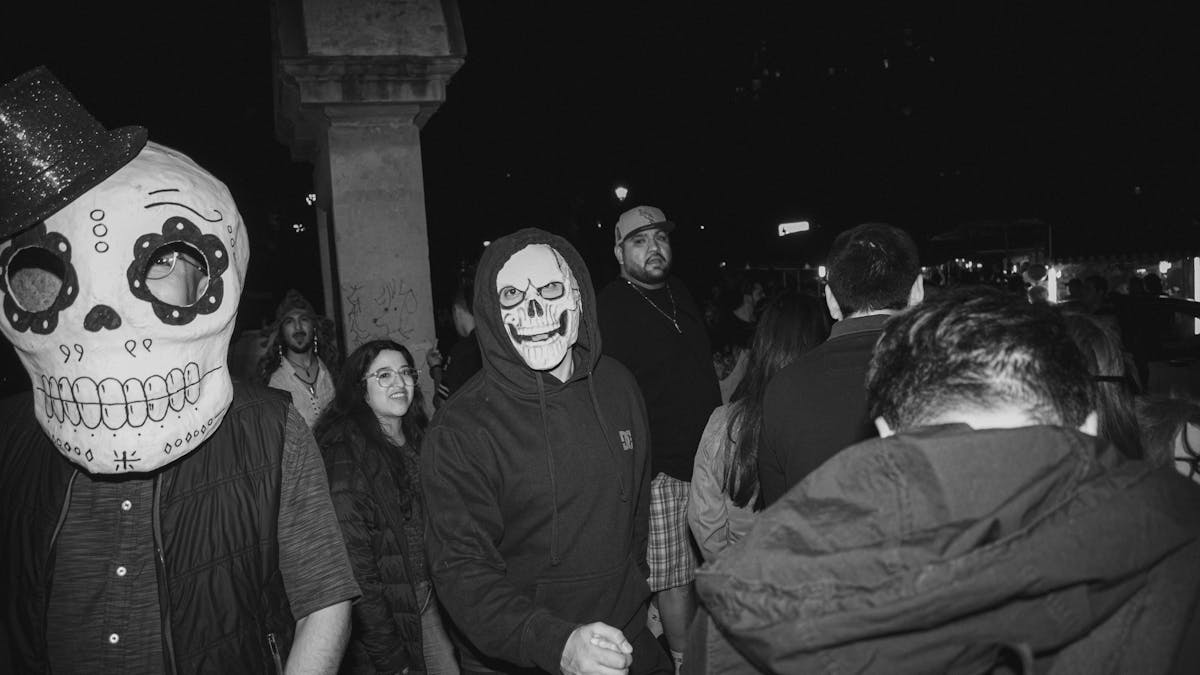 10 Truly Evil People Who Used Halloween as the Perfect Cover 4 Black and white photo of a Halloween celebration with people in spooky costumes and masks at night.