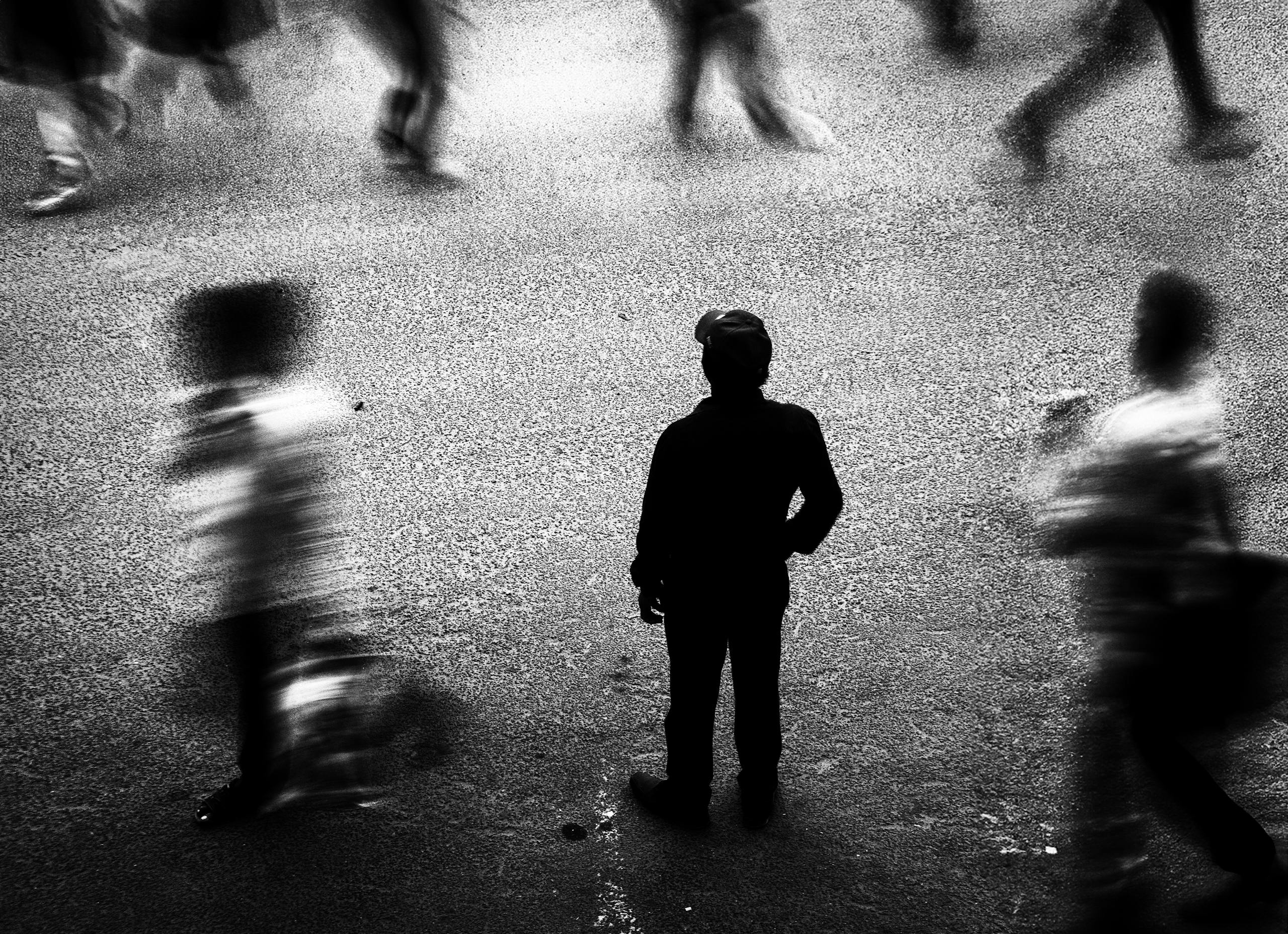 10 Disturbing Reasons Modern Friendships Are Falling Apart in America 1 Black and white photo of a lone silhouette in a bustling city street filled with motion blur.