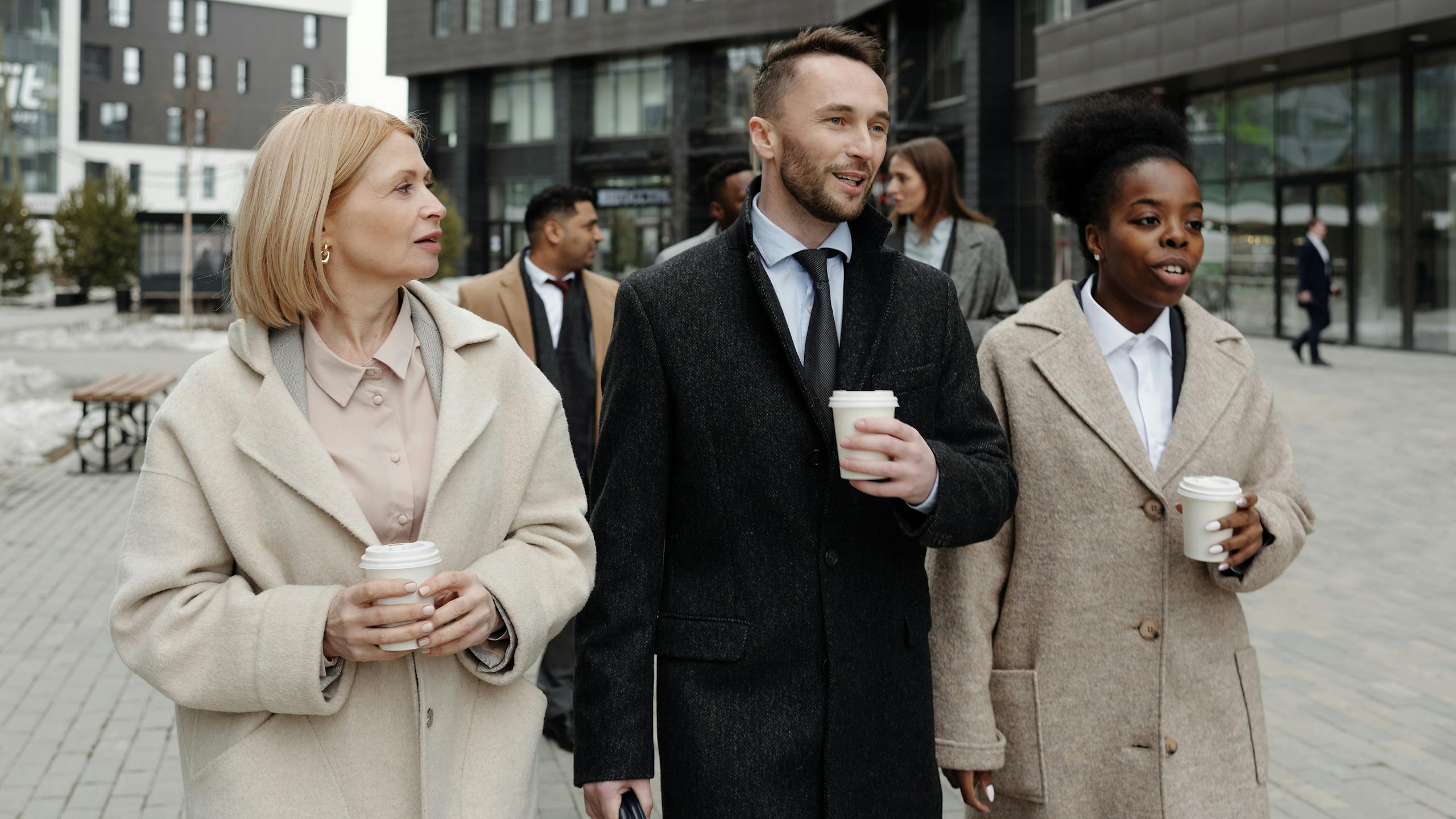 Business professionals discussing and enjoying coffee outdoors during a break.