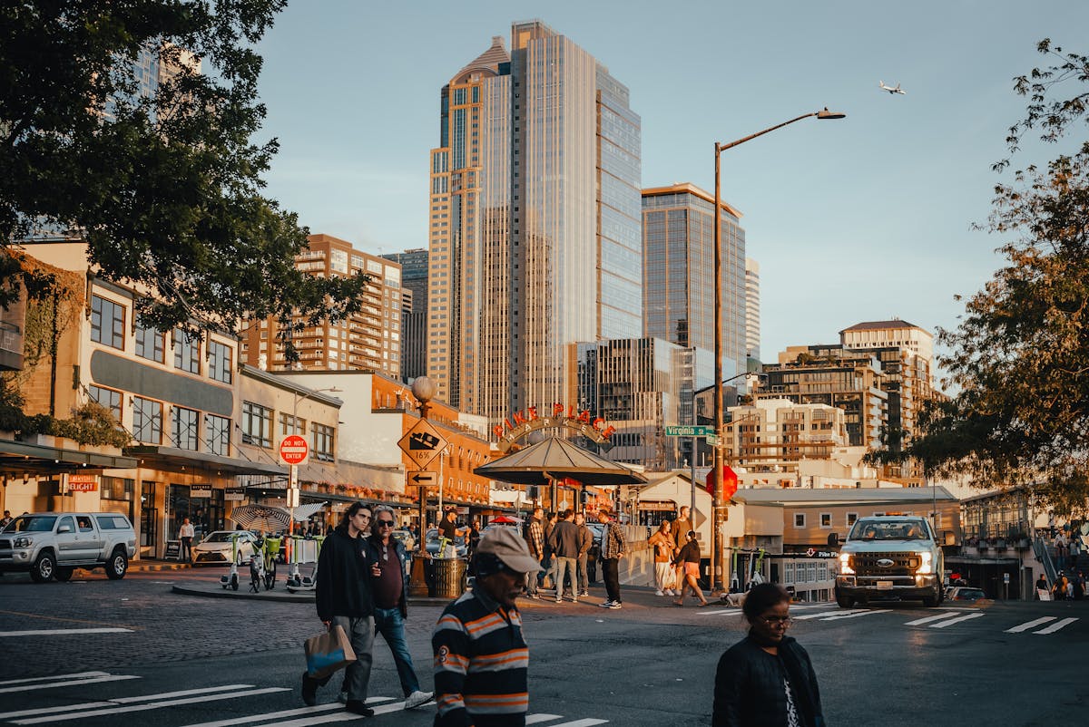 Bustling street view of Pike Place Market with skyscrapers in Seattle at sunset.