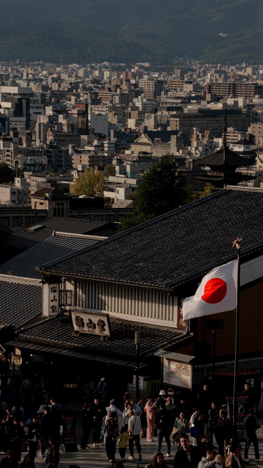 Cityscape view of Kyoto with traditional buildings and a visible Japanese flag, capturing Japan's essence.