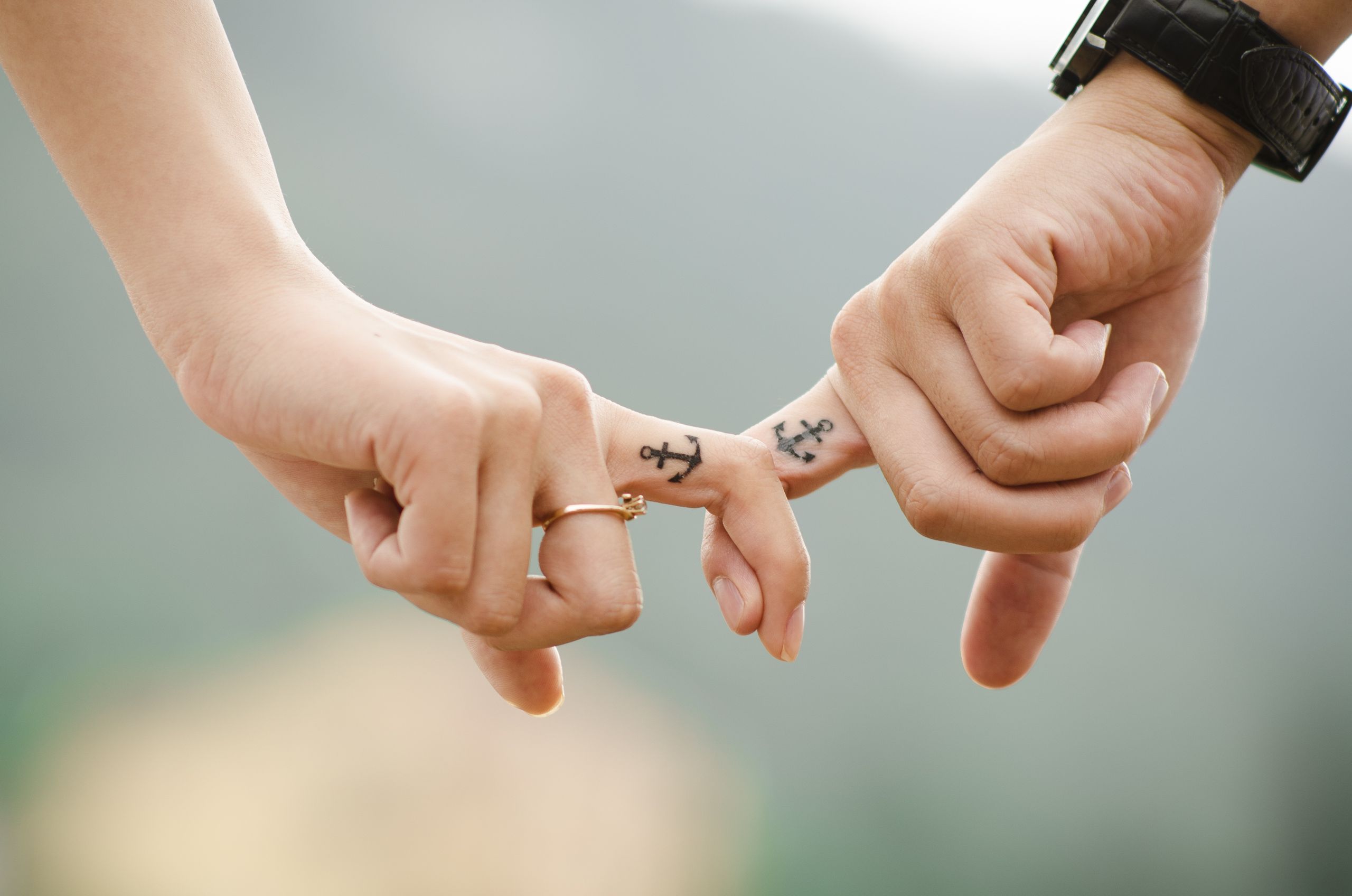 8 Warning Signs Your Relationship Is Quietly Falling Apart 5 Close-up of a couple holding hands, featuring anchor tattoos symbolizing love and connection.