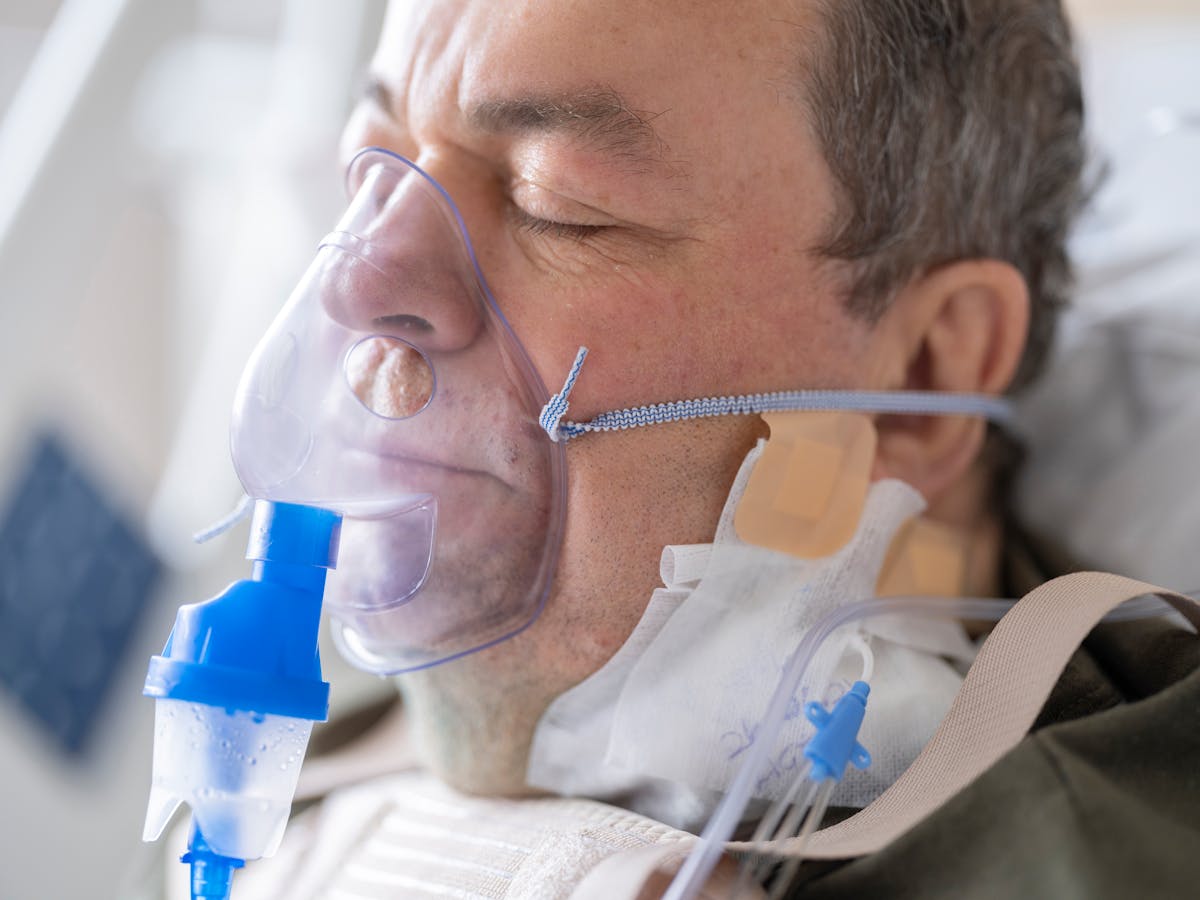 9 Silent Reasons People Die in Their Sleep, According to Science 5 Close-up of a senior patient wearing an oxygen mask in a hospital setting.
