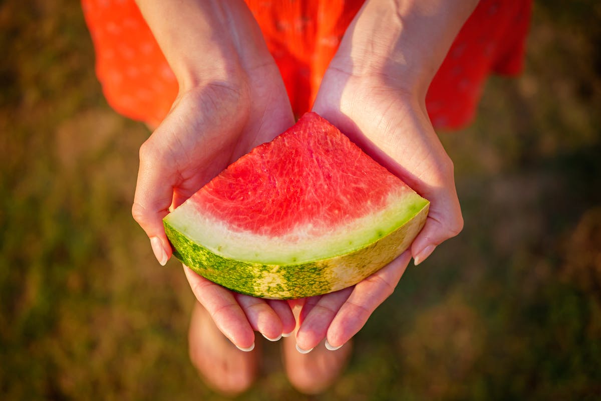 8 Things to Know Before You Put Watermelon in Your Grocery Cart 2 Close-up of a watermelon slice in hands, symbolizing summer freshness.