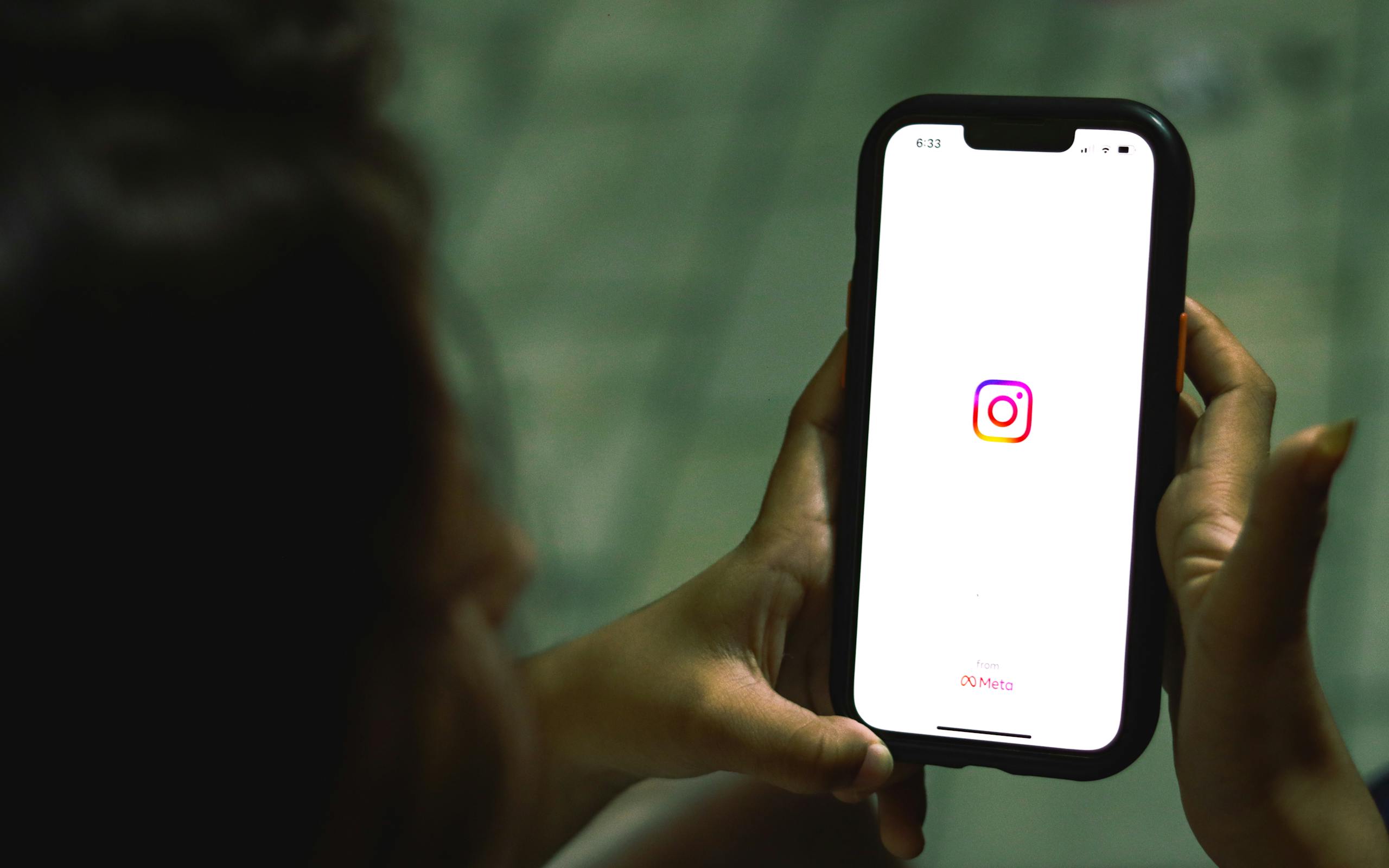 8 Ugly Reasons Social Media Is Destroying Attention Spans 3 Close-up of a woman holding a smartphone displaying the Instagram app indoors.