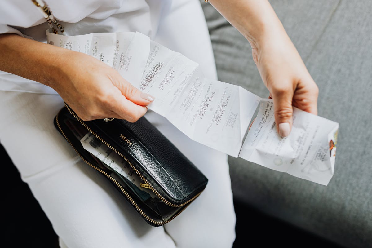 10 Things Boomers and Gen X Do That Make Gen Z Cringe Instantly 3 Close-up of a woman's hands managing multiple receipts taken from a black wallet.