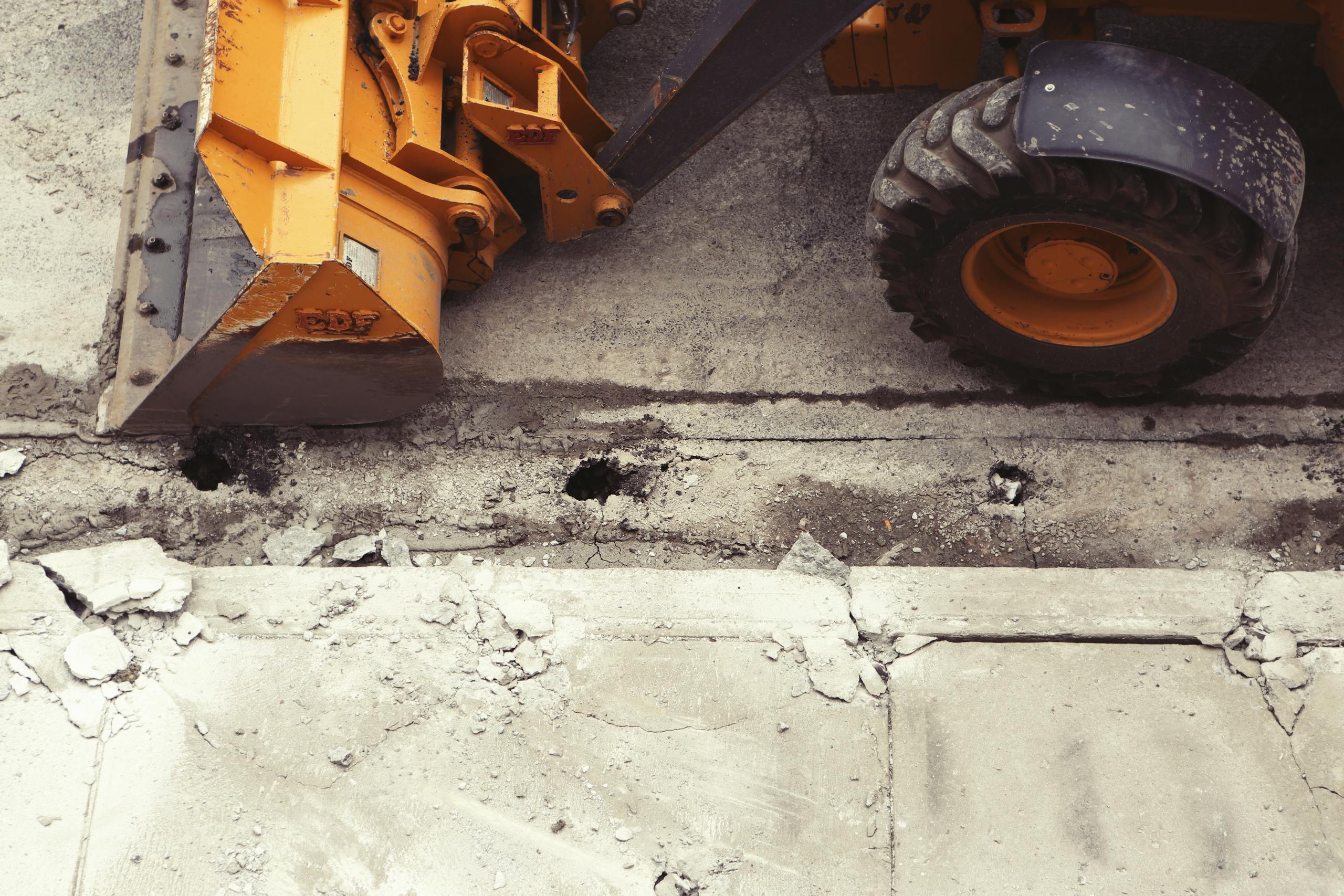 8 Disturbing Details About the Omaha Sinkhole That Swallowed Two Cars 4 Close-up of an excavator working on road construction, showcasing the industrial process.