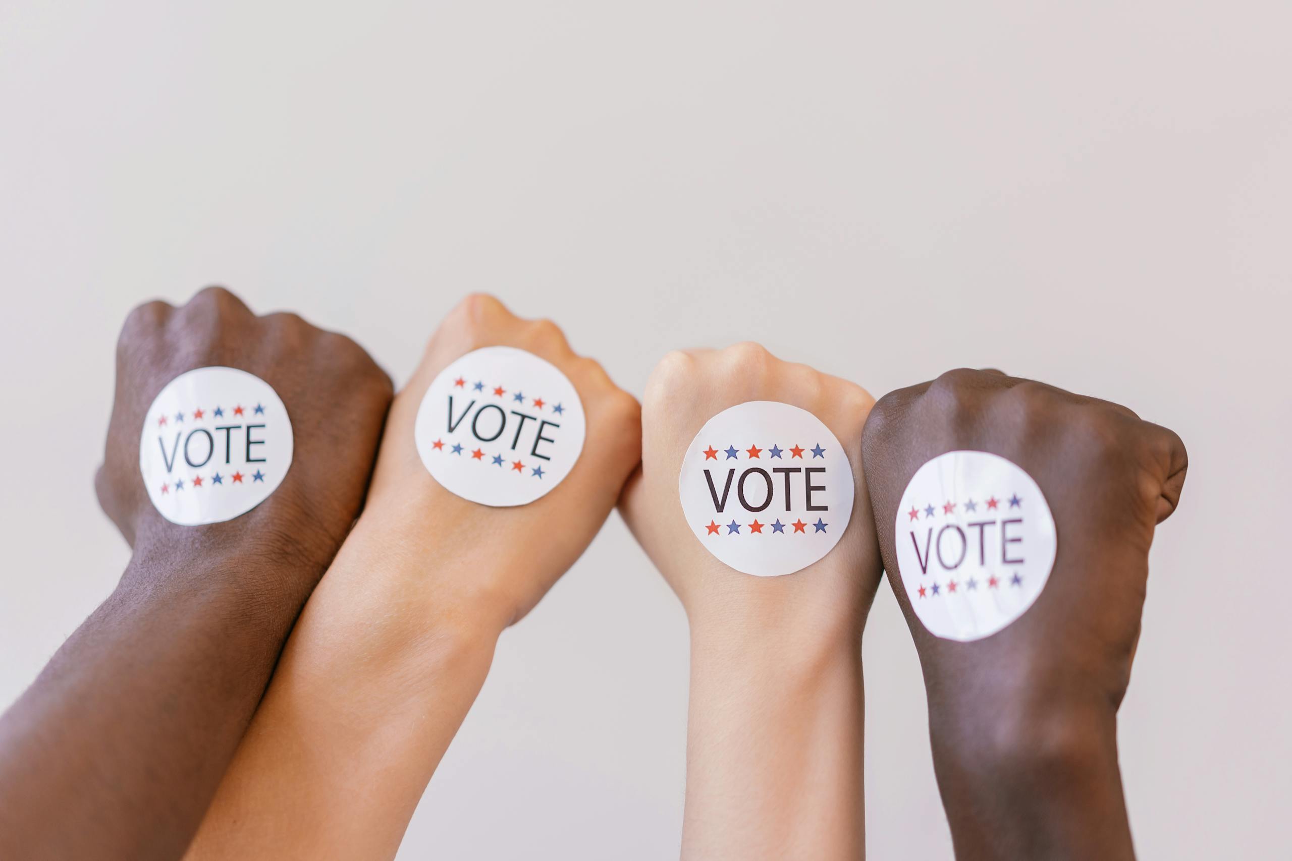 7 Reasons Gen X and Millennials Are to Blame for Bad Leadership in America 3 Close-up of diverse hands showing unity with vote stickers emphasizing democracy.