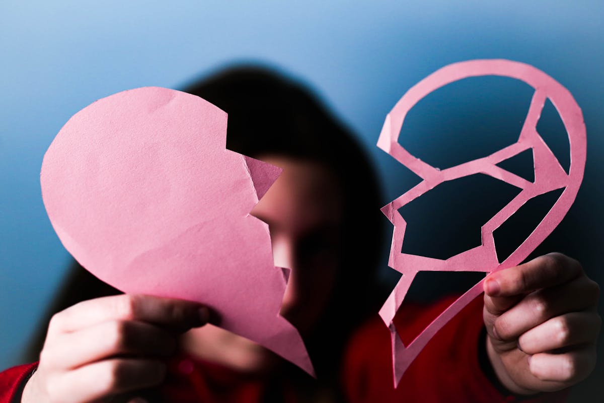 10 Warning Signs Your Friends Are Damaging Your Relationship And How You Can Protect It 1 Close-up of hands holding a pink broken paper heart, symbolizing love and heartbreak.