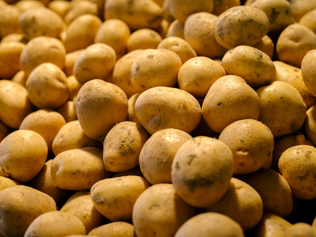 9 Common Foods That Could Be Riskier Than You Think 3 Close-up view of fresh yellow potatoes stacked together, ideal for food and abundance themes.
