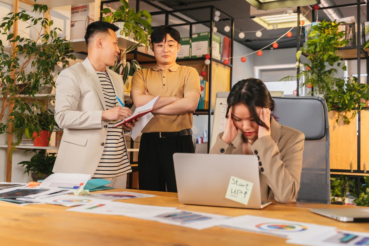 Colleagues engaged in a discussion in a modern office setting with indoor plants and documents.Lack of Appreciation in the office