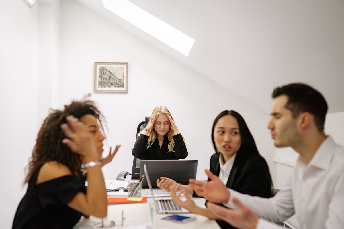 Colleagues in a heated discussion around a desk, highlighting workplace stress and tension. poor Communication