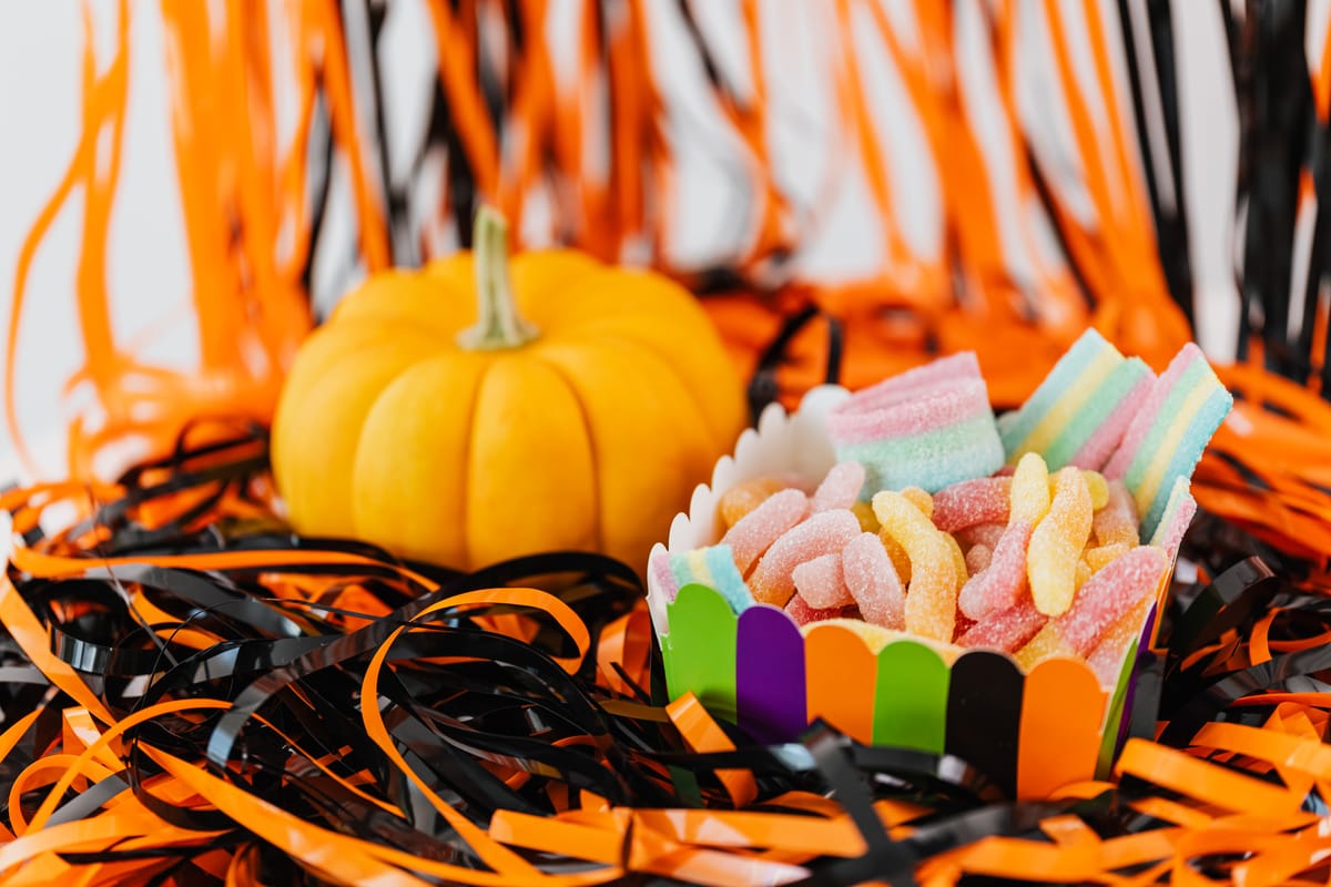 10 Truly Evil People Who Used Halloween as the Perfect Cover 3 Colorful candies in a vibrant box next to a small pumpkin surrounded by Halloween-themed decorations.
