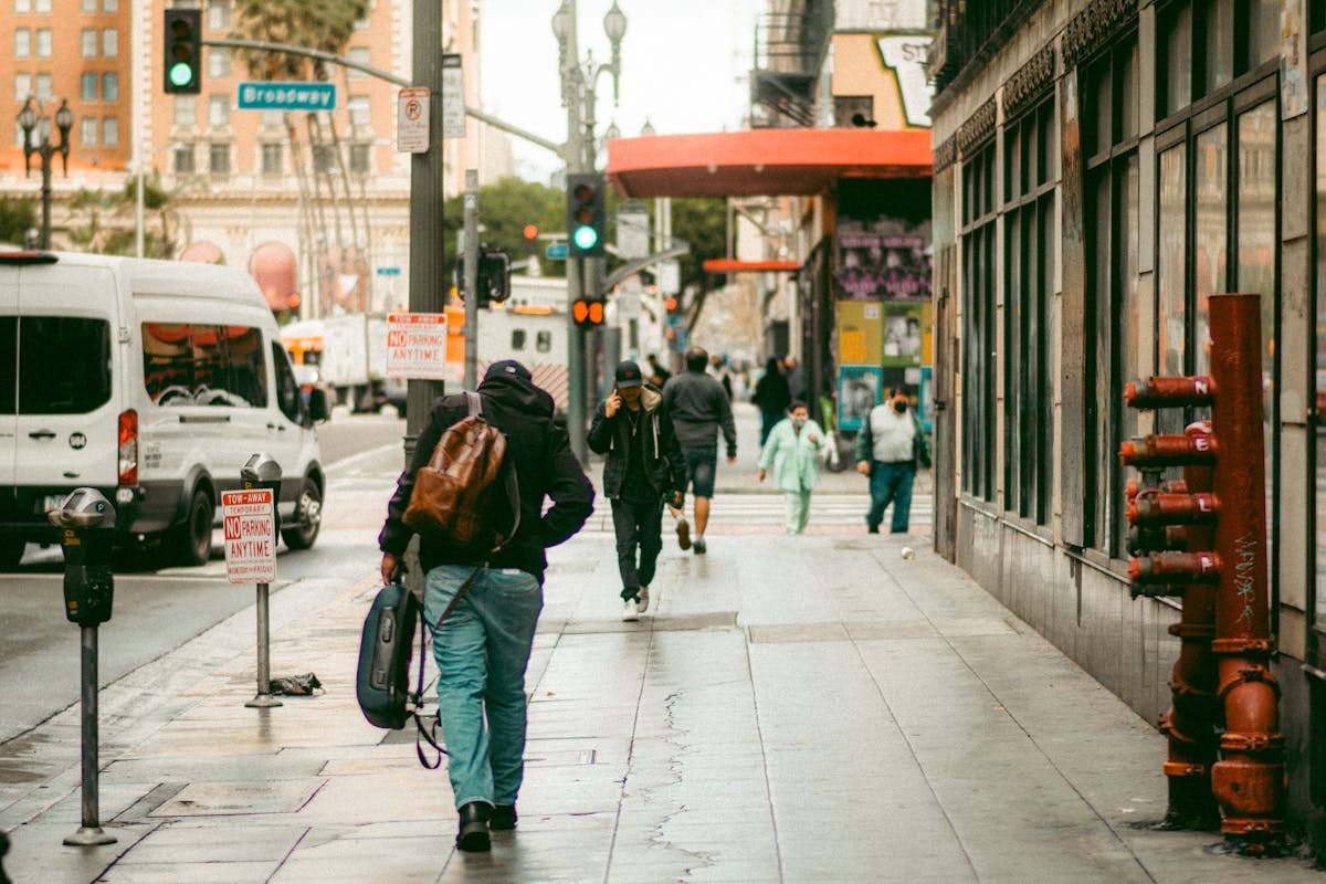 Commuters walk along wet sidewalks in downtown Los Angeles after rain, capturing the essence of city life.