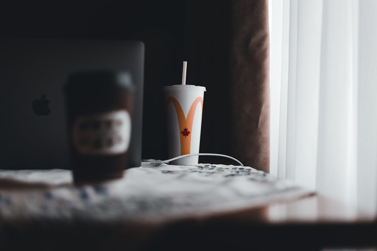 Cozy indoor scene with coffee cup and laptop on table by window light.