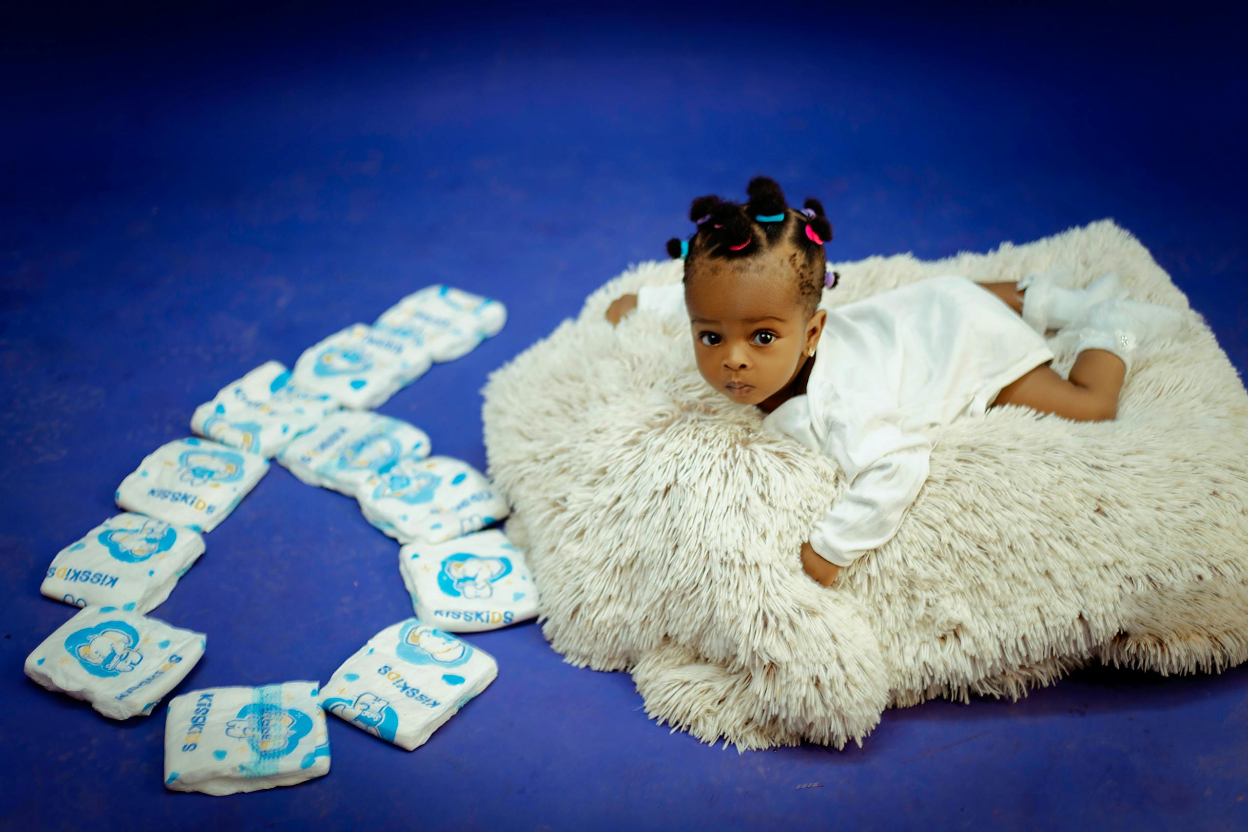 7 Uncomfortable Reasons More Women Are Saying No to Motherhood 1 Cute baby lying on a soft rug with diapers arranged in a heart shape.