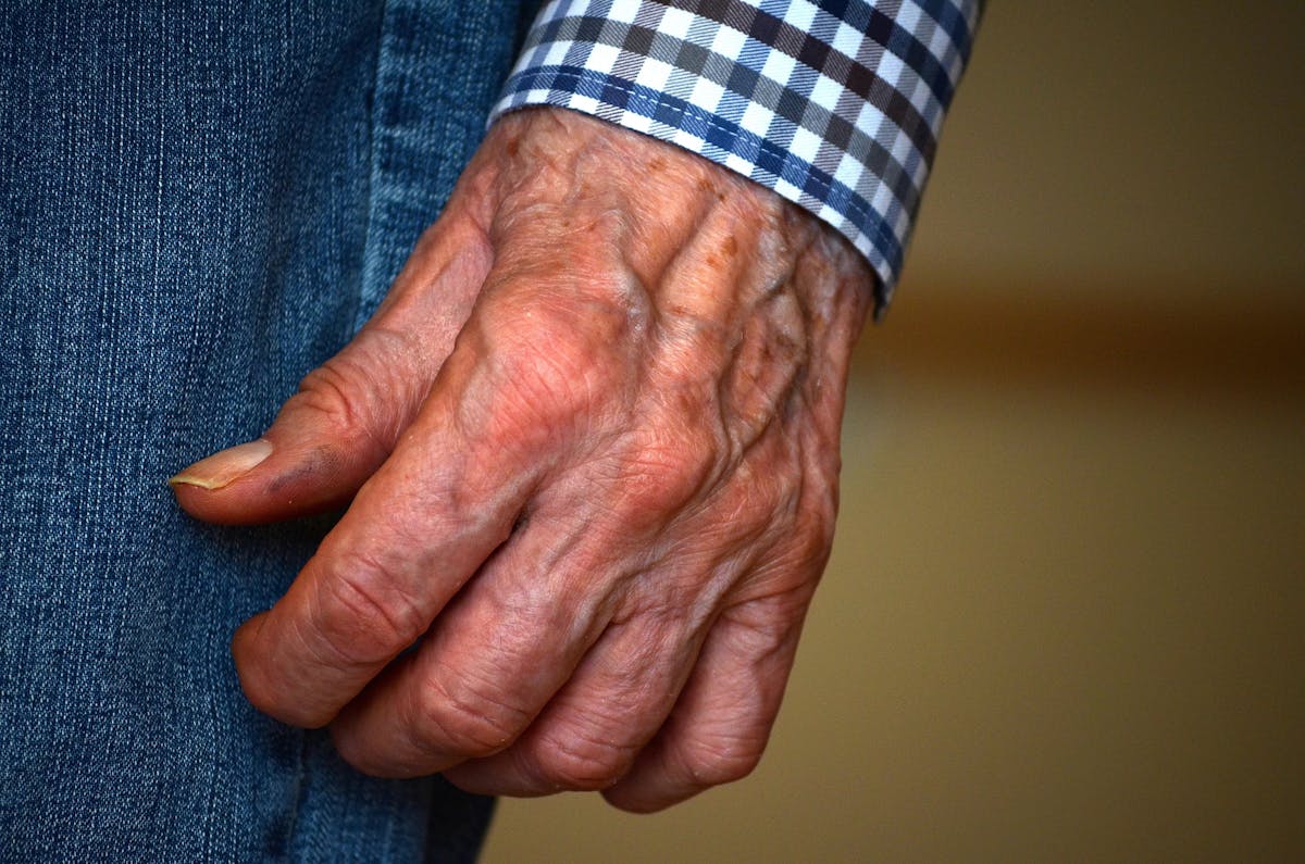 Detailed close-up image of a senior adult's wrinkled hand against a plain background.