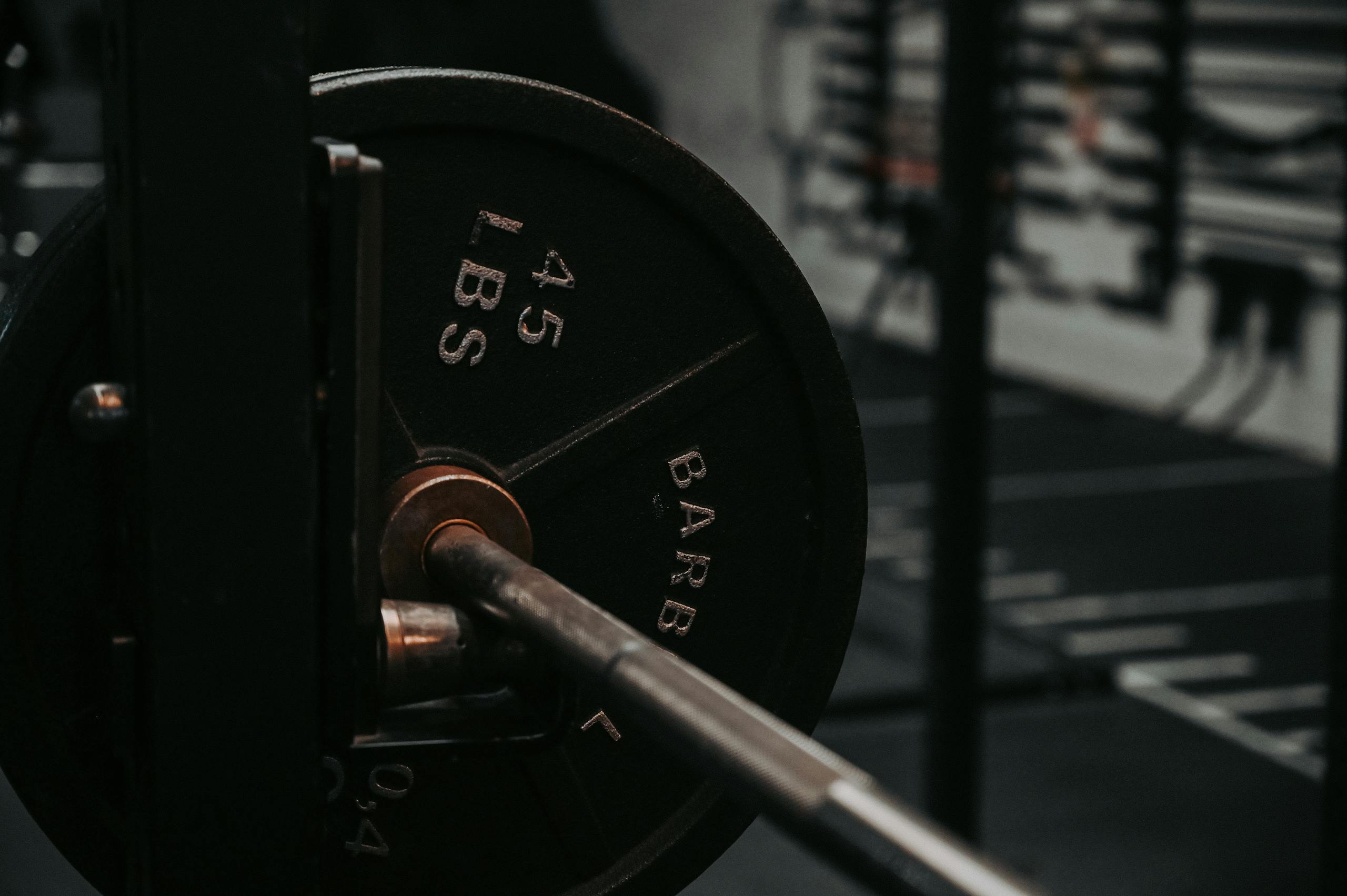 8 Gym Accidents That Went Horribly Wrong 2 Detailed close-up of a heavy barbell loaded with a 45 lbs weight plate in a gym setting.