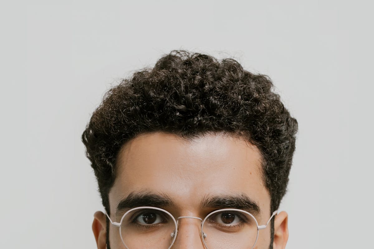 Genetic traits you might not know are inherited 5 Detailed close-up portrait of a man with curly hair and eyeglasses.