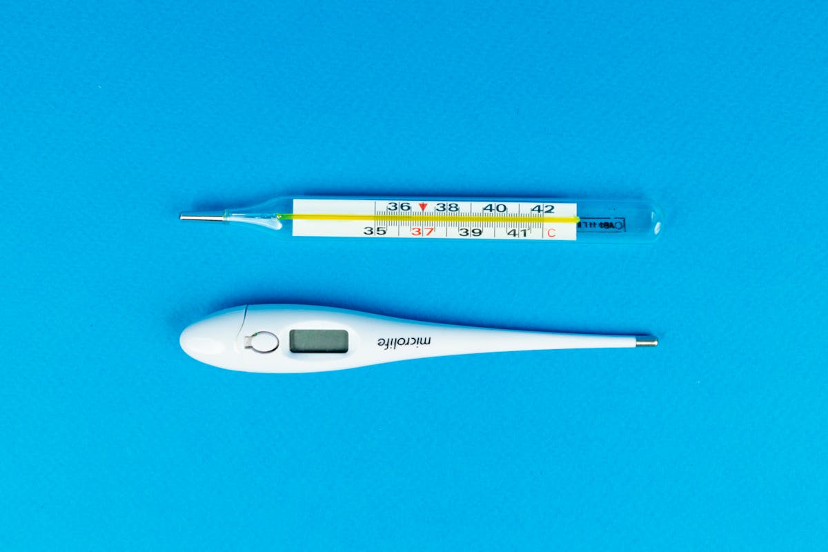 Digital and mercury thermometers on blue background for medical concept.