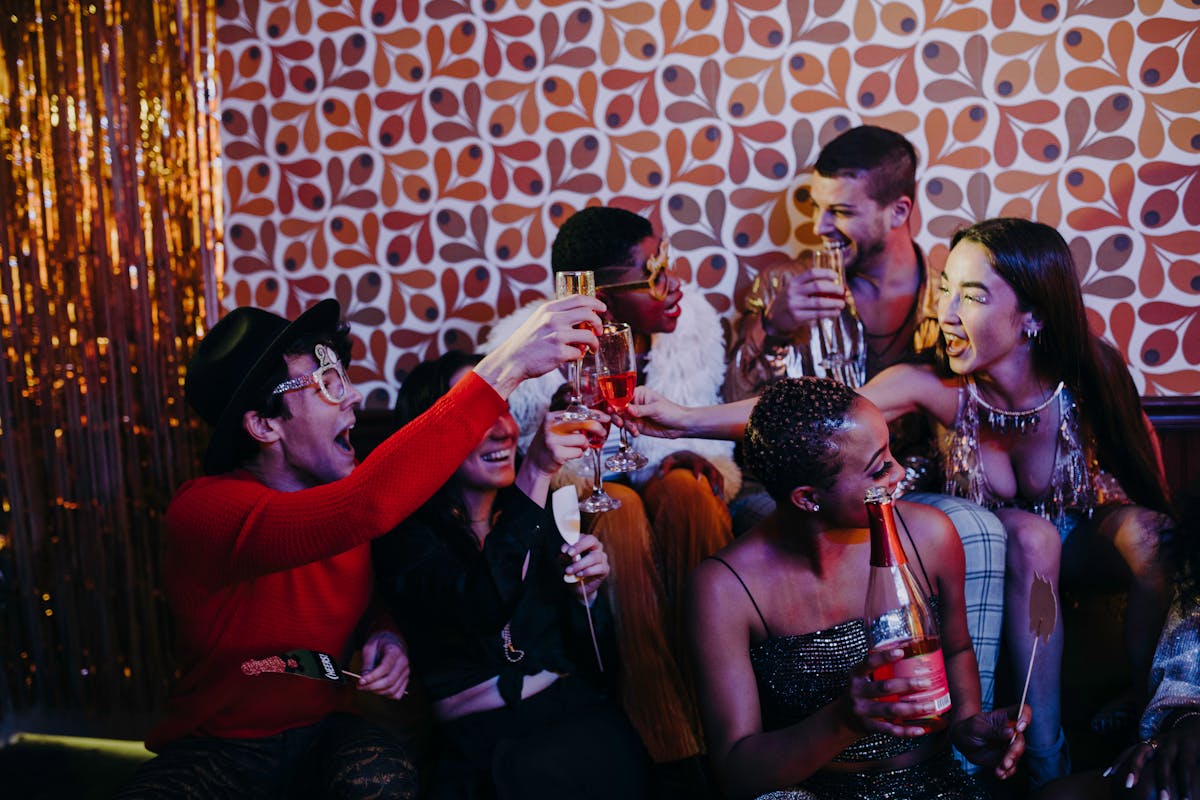 Diverse group of friends celebrating with drinks, creating joyful memories indoors.