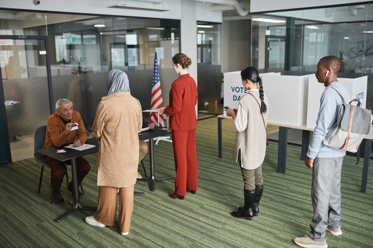 Trump Claims “Real Polling Numbers” Show Different Picture, but Provides No Evidence 2 Diverse group of voters lining up at an indoor polling station on election day.