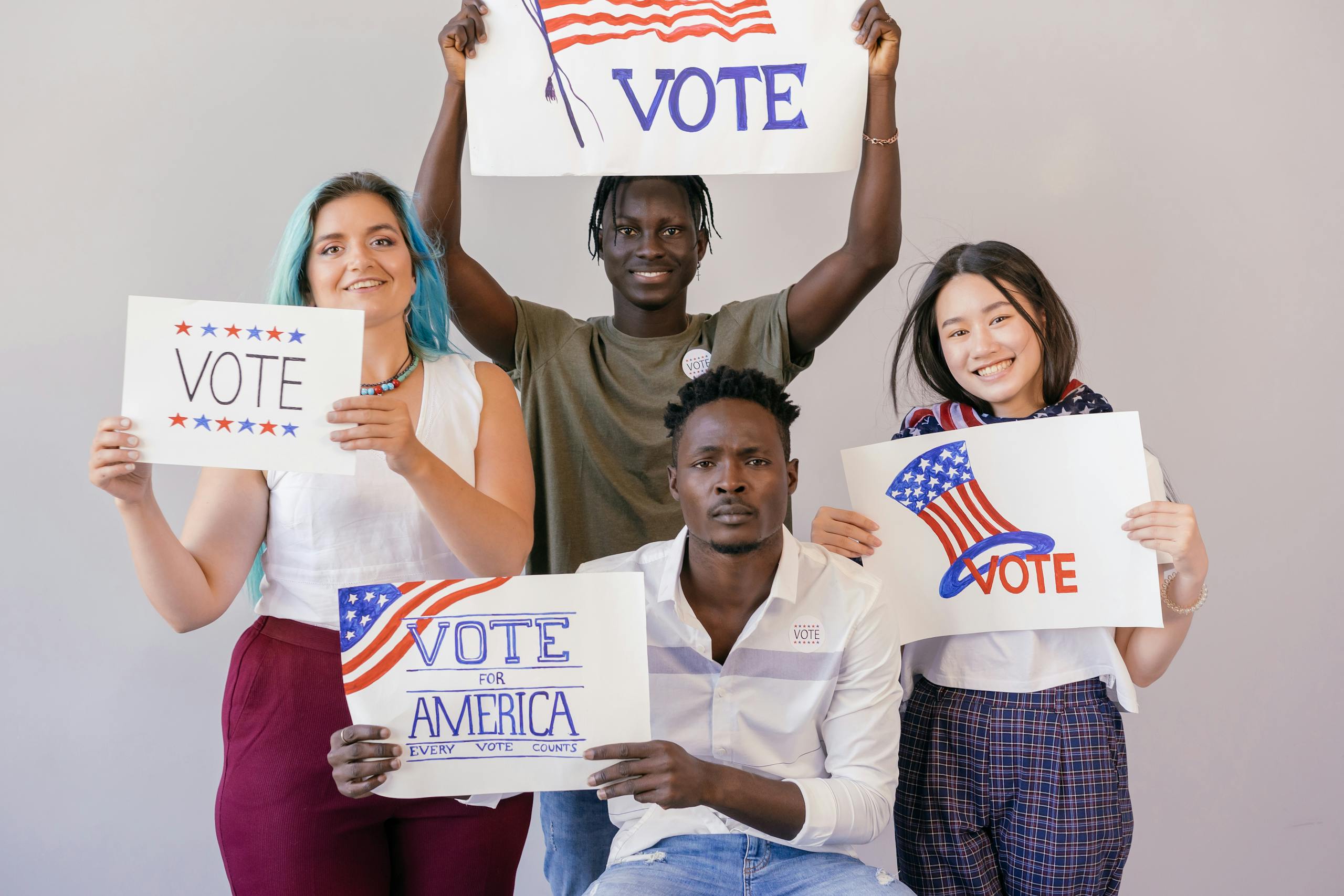 7 Reasons Gen X and Millennials Are to Blame for Bad Leadership in America 1 Diverse group of young adults proudly holding signs to encourage voting in America.