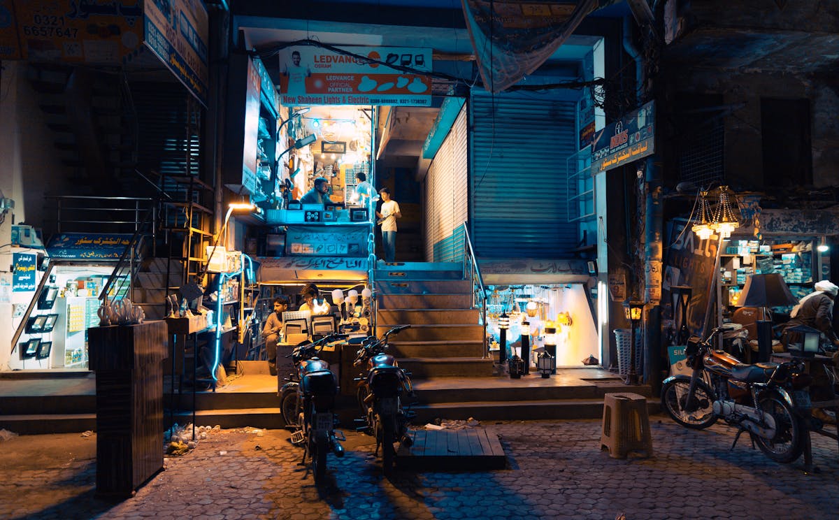 8 Cities With the Worst Air Quality Globally 3 Dynamic nighttime street scene in Faisalabad, Pakistan, showcasing a bustling local market with bright lights.
