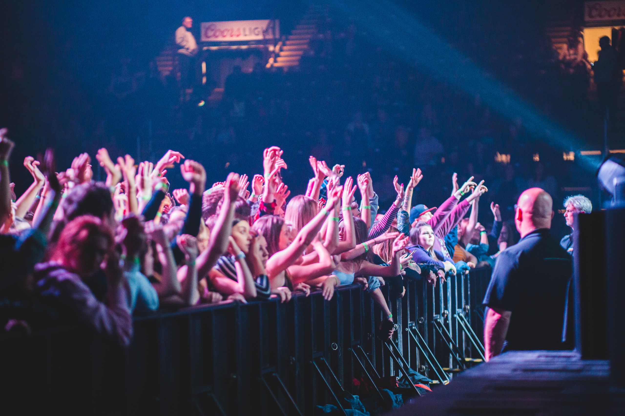 Excited crowd with hands up at a vibrant live music concert indoors.