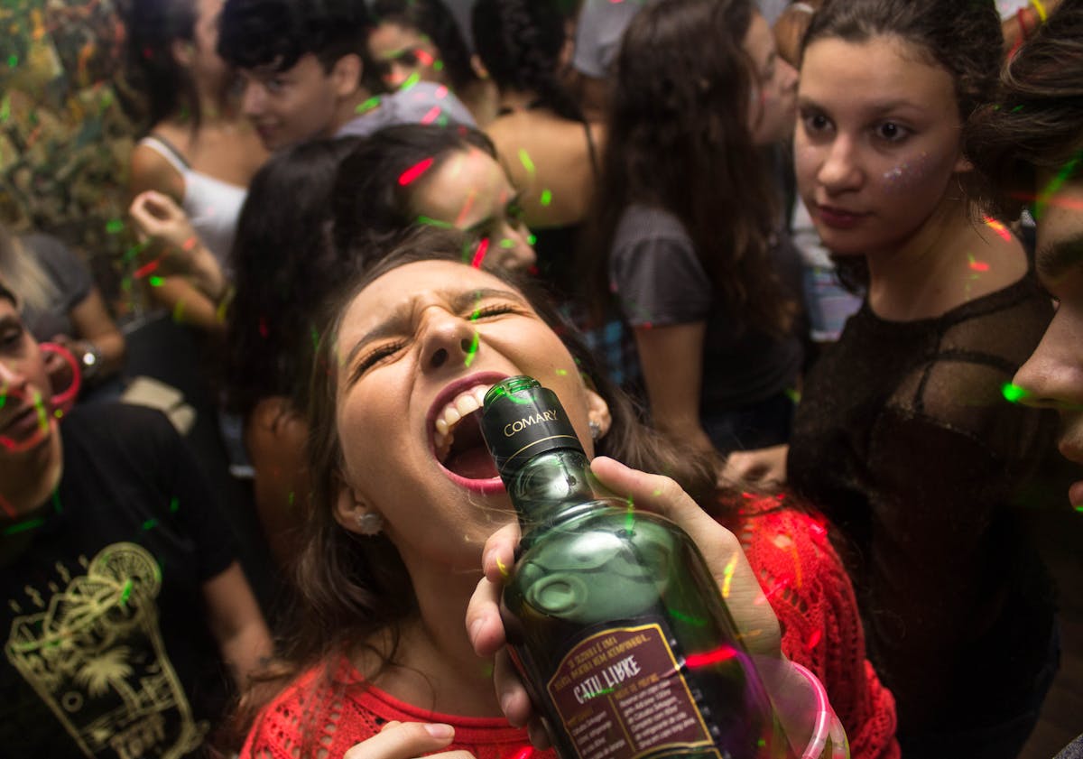 8 Disturbing Truths About Getting Drunk 3 Exciting party scene with young adults enjoying drinks and dancing under colorful lights.