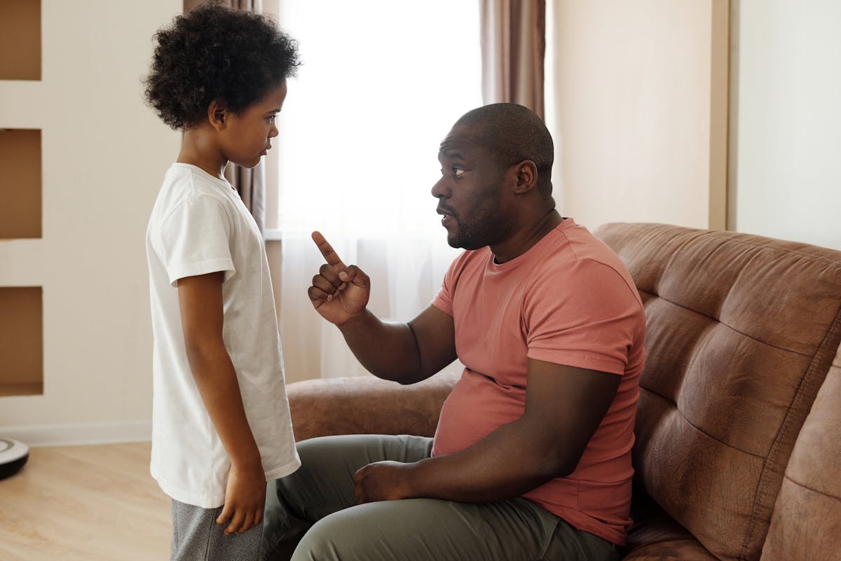 10 Everyday Things Kids Do That Drive Parents Insane 2 Father and son engaged in a heartfelt conversation on the sofa, illustrating parenting in a loving family setting.