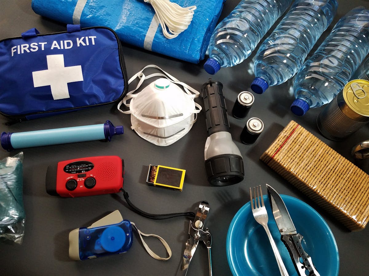America’s Emergency Readiness Website Is Urging Families to Prepare Now as Disasters Become More Frequent 2 Flat lay of essential emergency survival kit items including first aid and water bottles.
