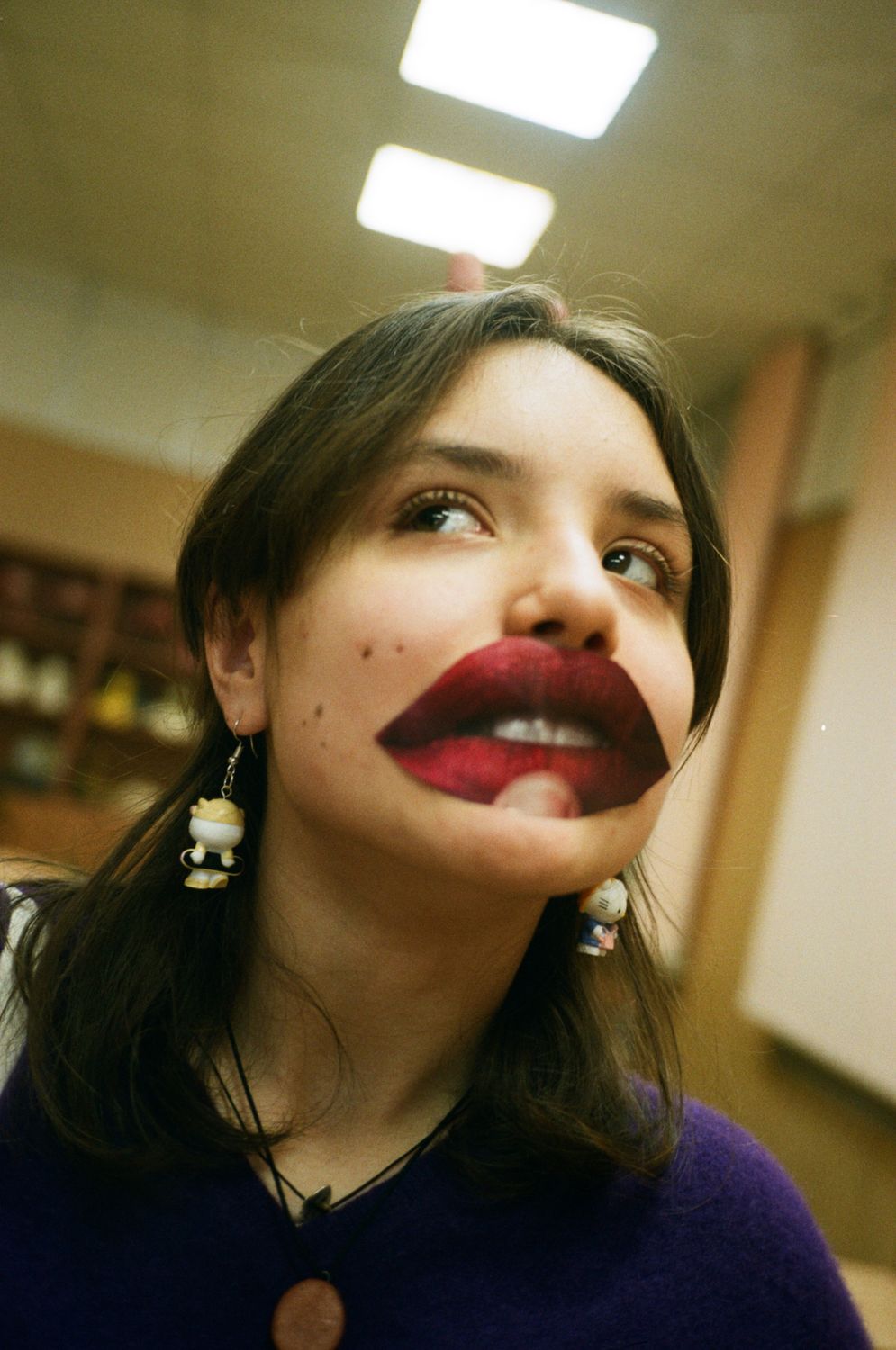12 Shocking Lip Injection Facts That Could Ruin Your Face 1 Funny adolescent in earrings with colorful decorative lips looking away under ceiling with glowing lamps