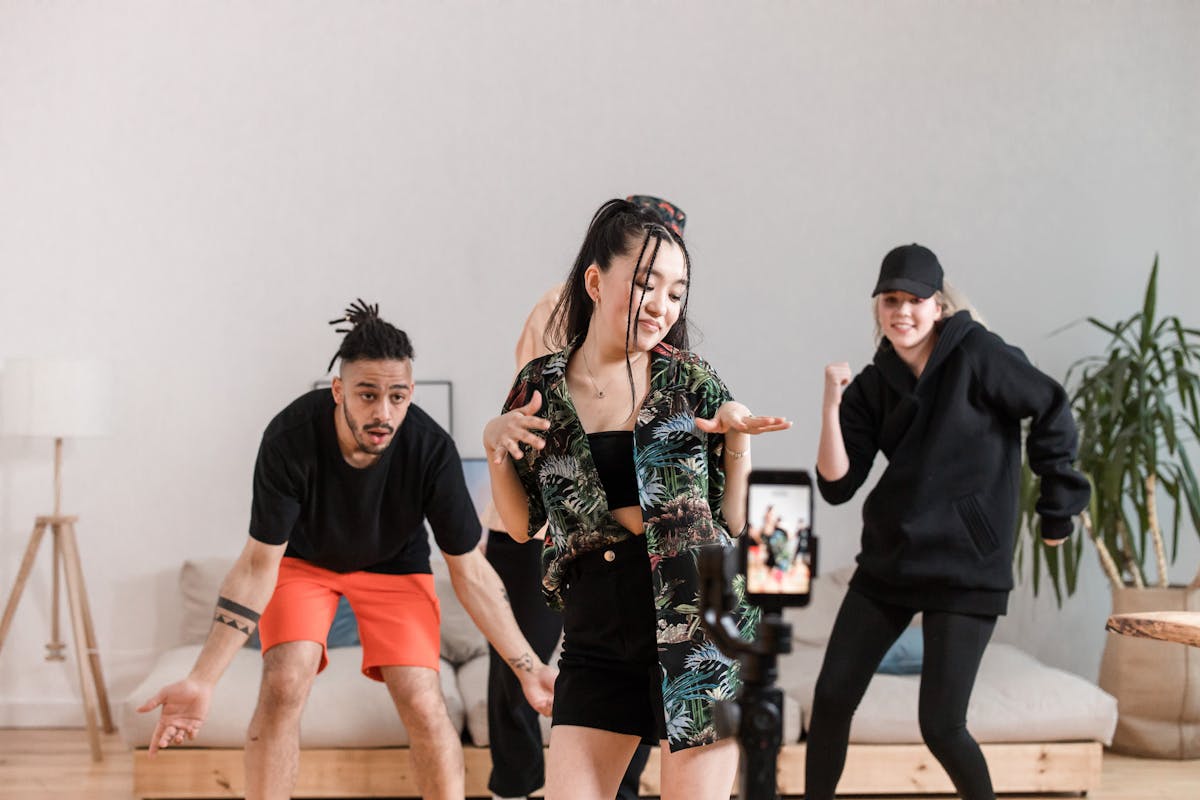 10 Gen Z Habits That Quietly Irritate Millennials 1 Group of diverse young adults dancing and recording content indoors with a smartphone.