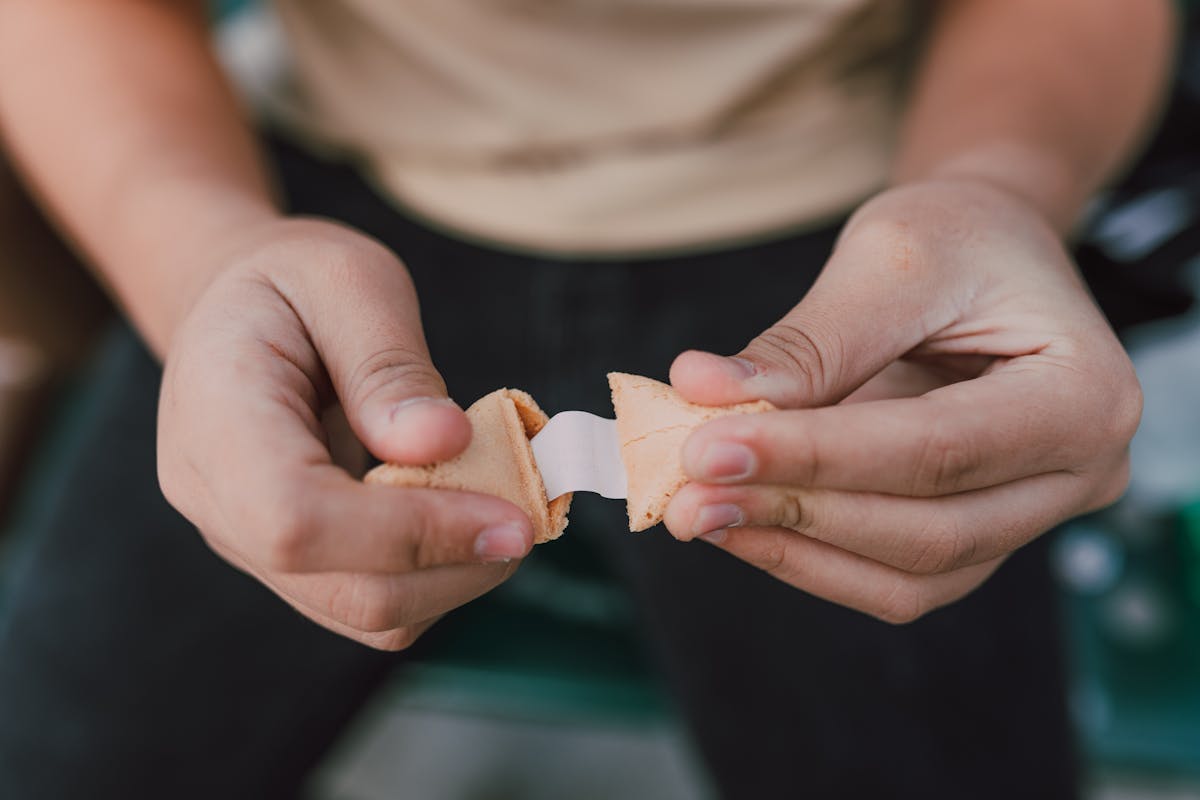 Hands breaking open a fortune cookie with a blank paper slip emerging.