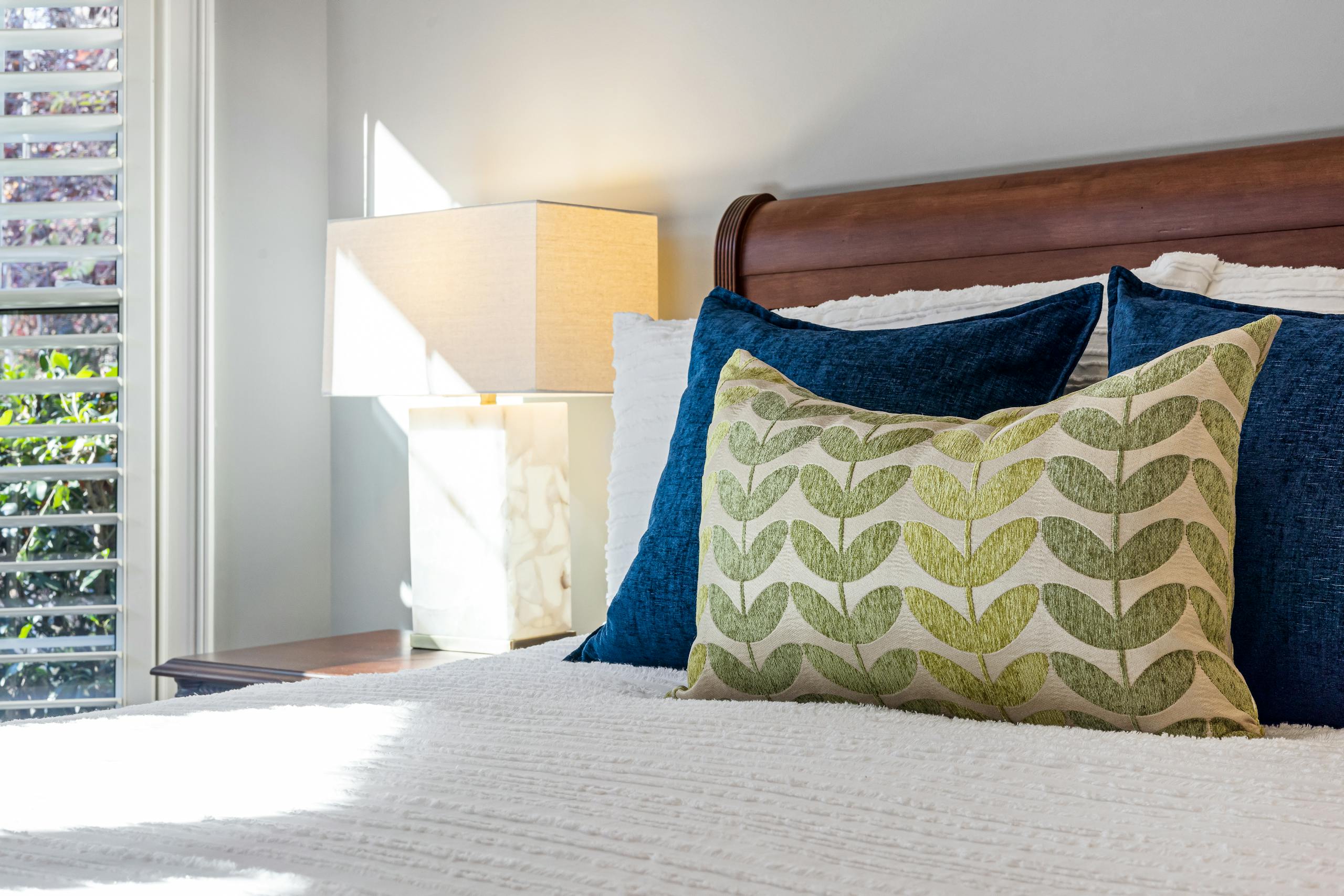 8 Hotel Mistakes That Can Ruin Your Stay 4 Inviting bedroom with decorative pillows and warm sunlight filtering through windows.