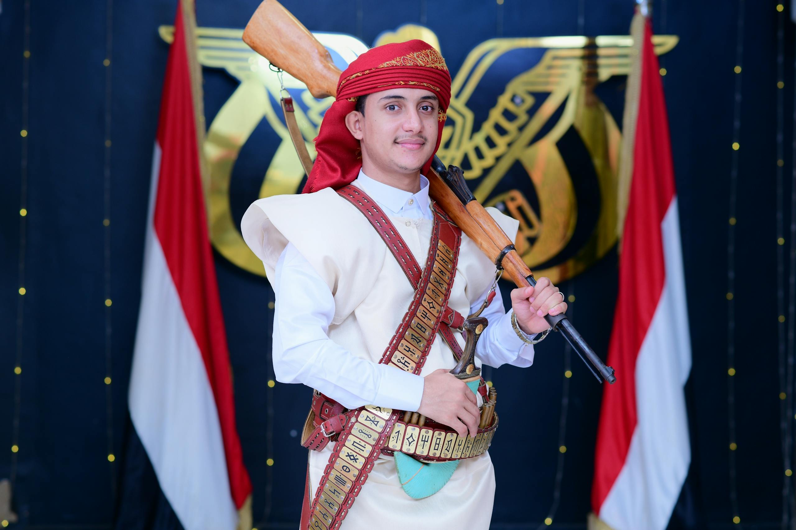Man in traditional Yemeni attire with rifle, cultural background.