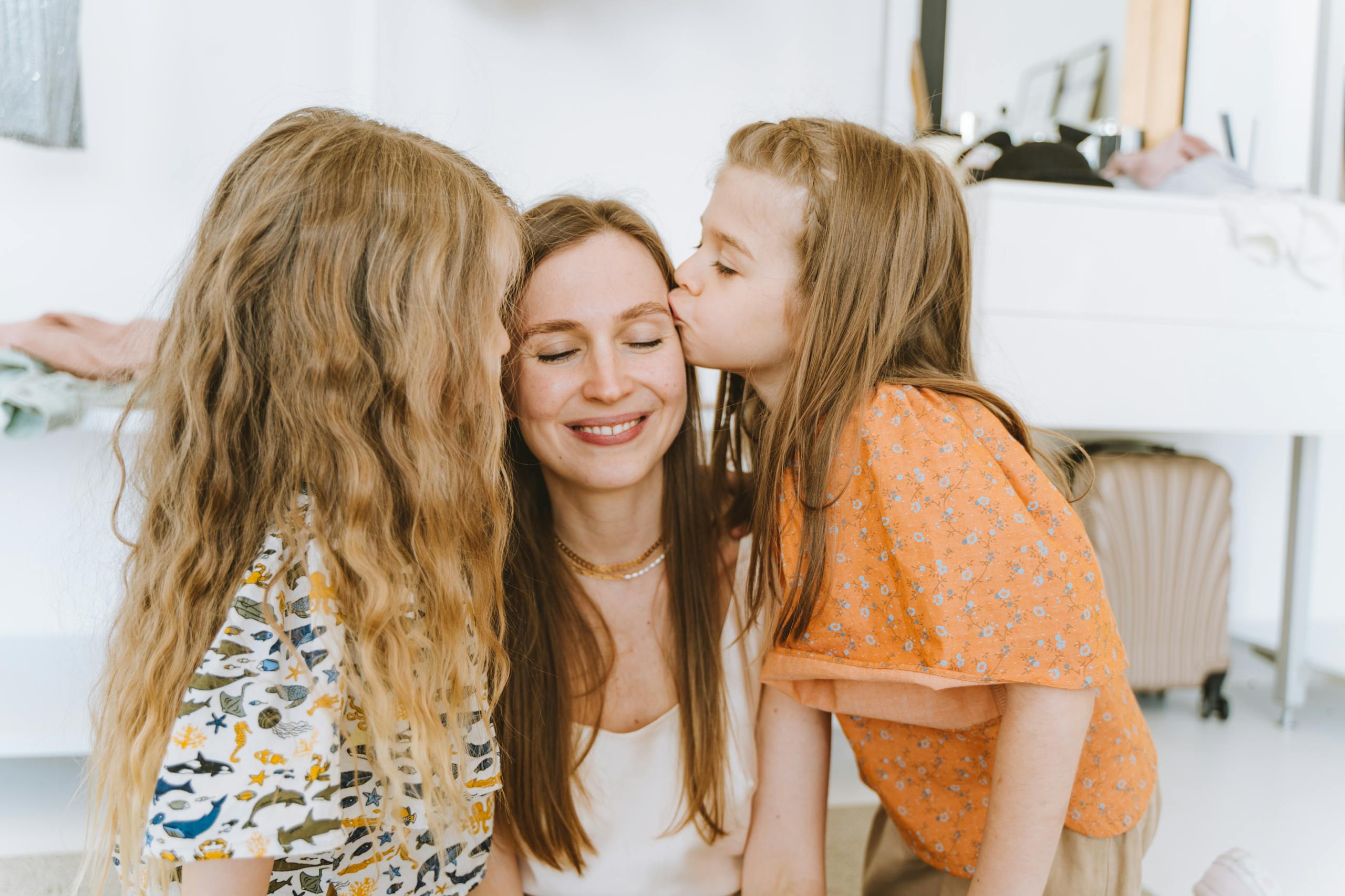 Mother and daughters enjoying a loving moment inside a cozy room.
