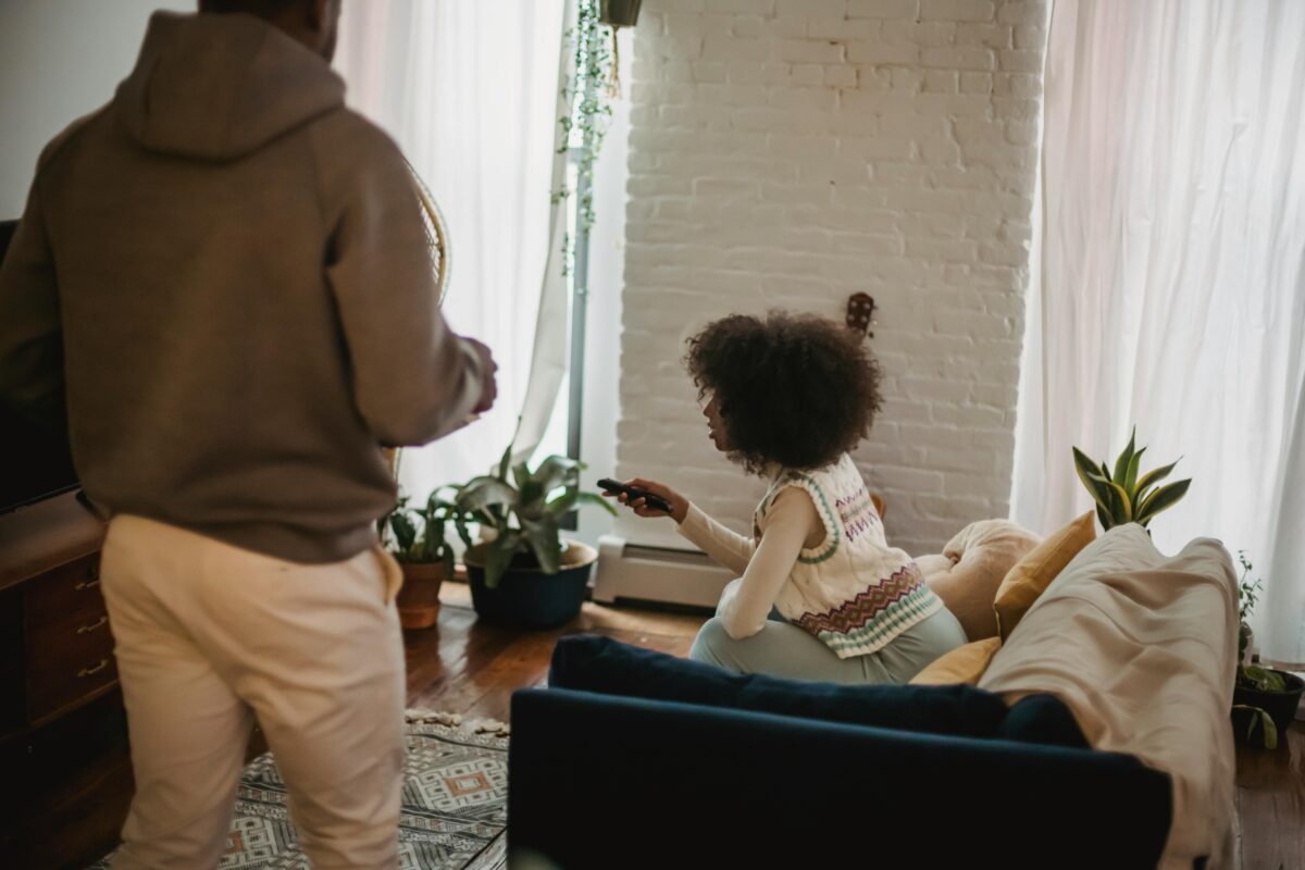 unrecognizable-black-man-walking-in-living-room-while-girlfriend-watching-tv