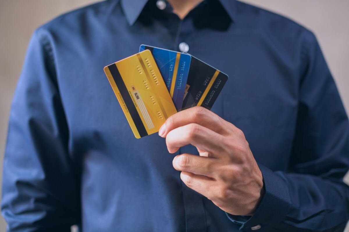man-in-blue-dress-shirt-holding-three-credit-cards-