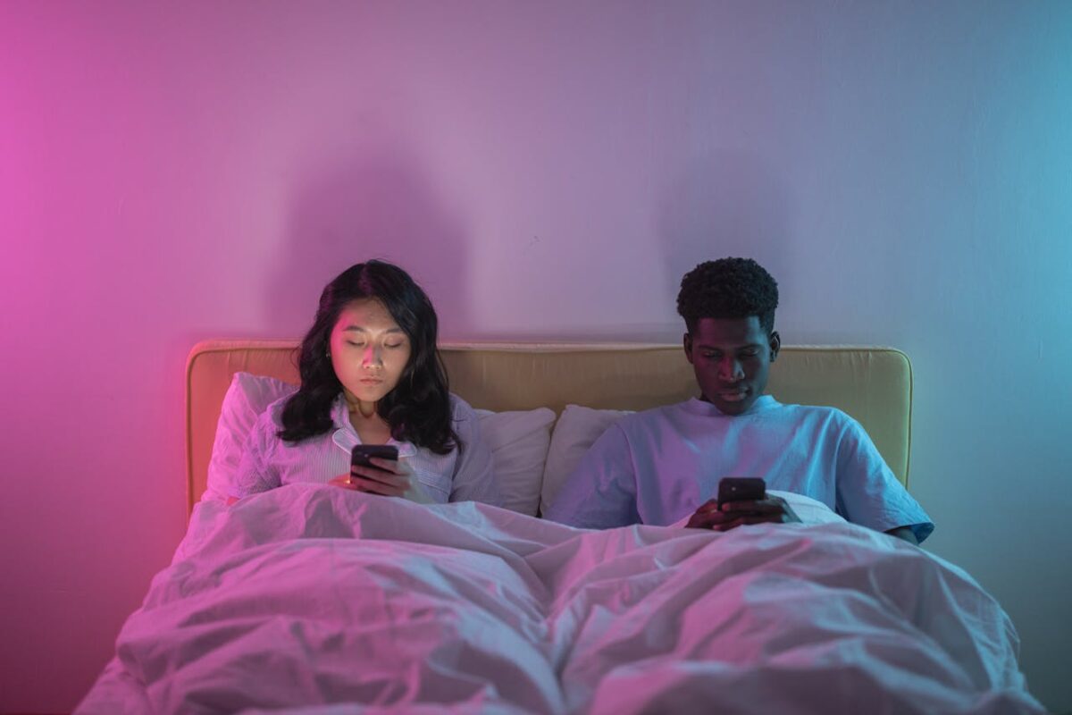 /man-and-woman-lying-on-bed-while-using-phone-