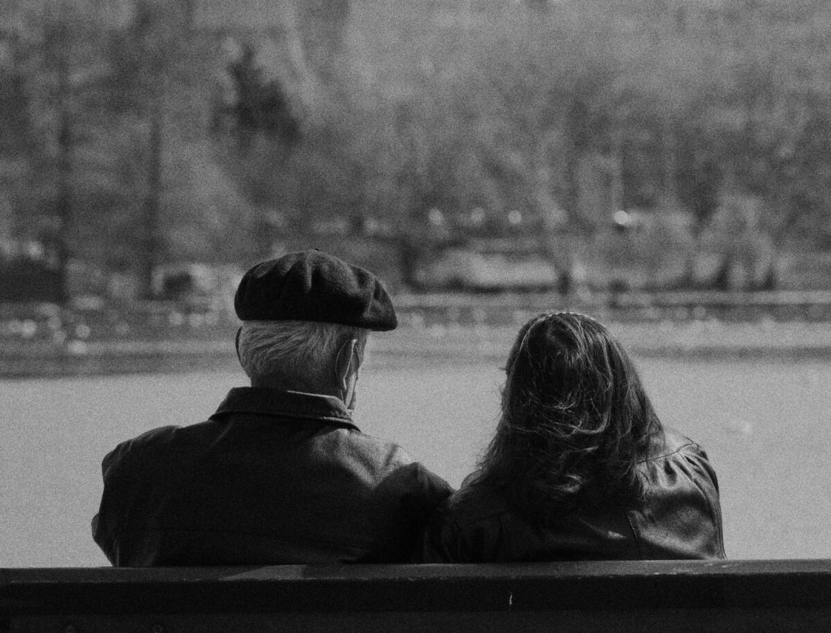 grayscale-photo-of-a-romantic-couple-sitting-on-the-bench
