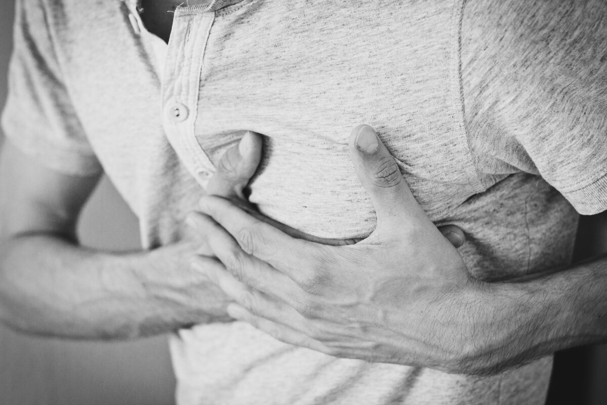 6 Symptoms You Should Never Dismiss as Normal Aging 2 Black and white photo of a man clutching his chest, indicating discomfort or pain.