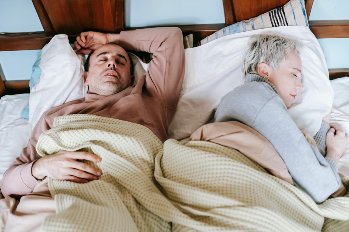 diverse-spouses-sleeping-on-bed-under-plaid