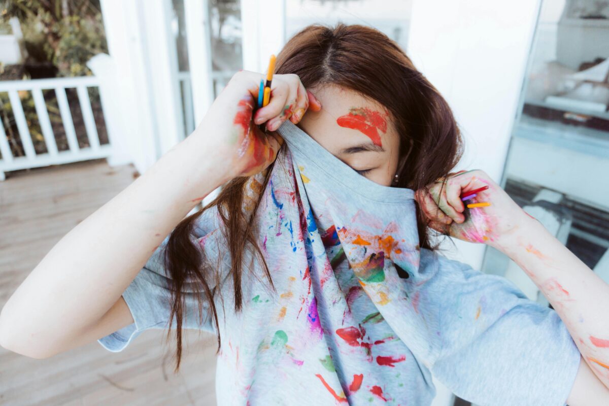 close-up-shot-of-a-person-with-watercolors-on-her-hands-and-face