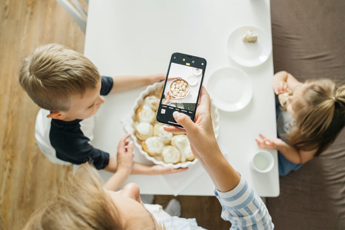 9 Ways Social Media Encourages Fake Happiness and Quietly Warps Real Life 1 person-holding-a-smartphone-taking-photo-of-food