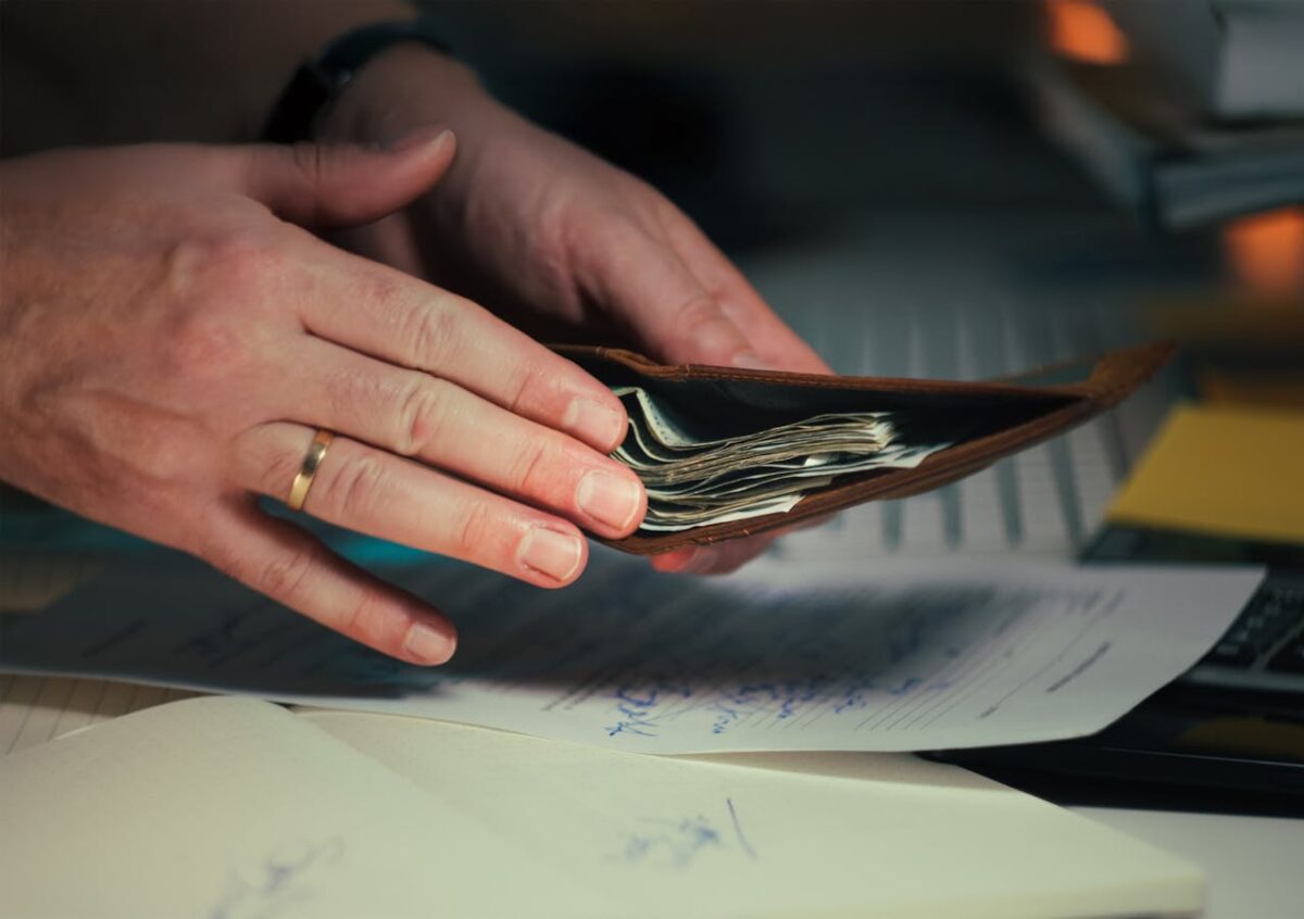 close-up-of-hands-handling-wallet-with-cash-and-documents-