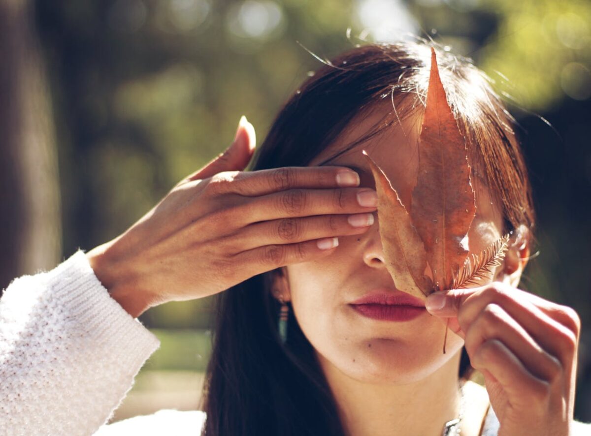 woman-covering-face-with-leaf-and-hand